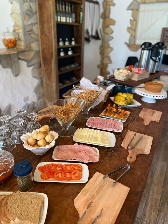 Mesa do café com granola, frios, tomate e mamão