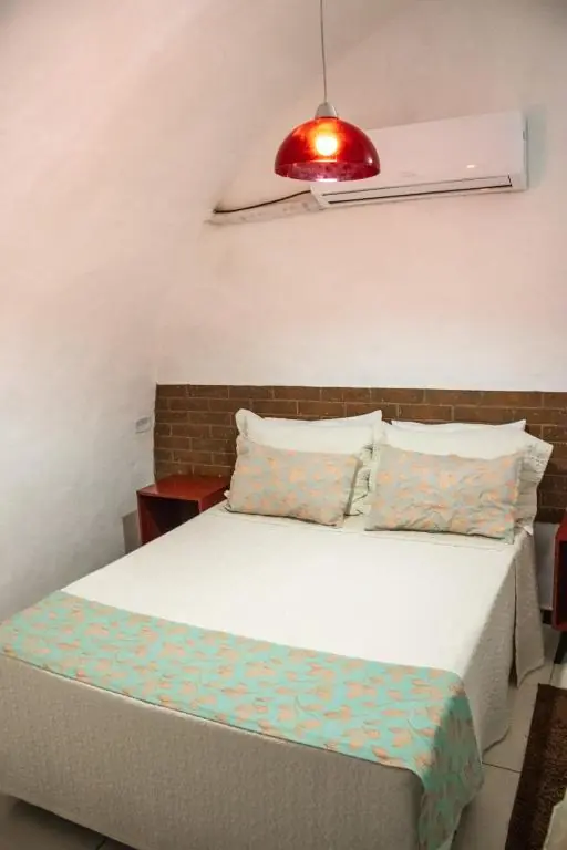 Quarto de teto curvo com cama de casal e luminária vermelha