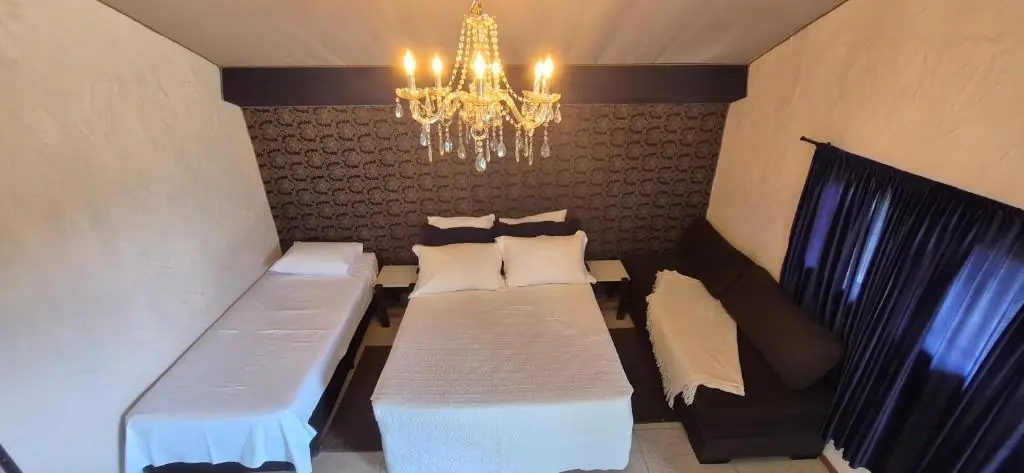 Quarto com cama de casal, cama de solteiro e sofá sob teto inclinado
